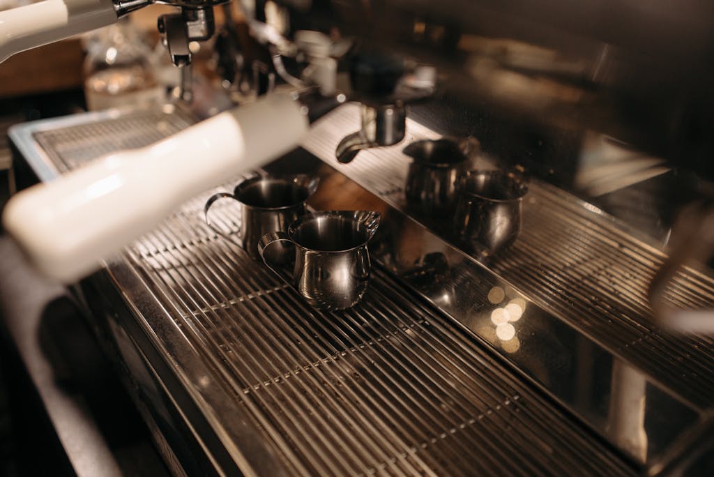 A detailed view of an espresso machine with metal frothing jugs ready for use in a coffee shop.